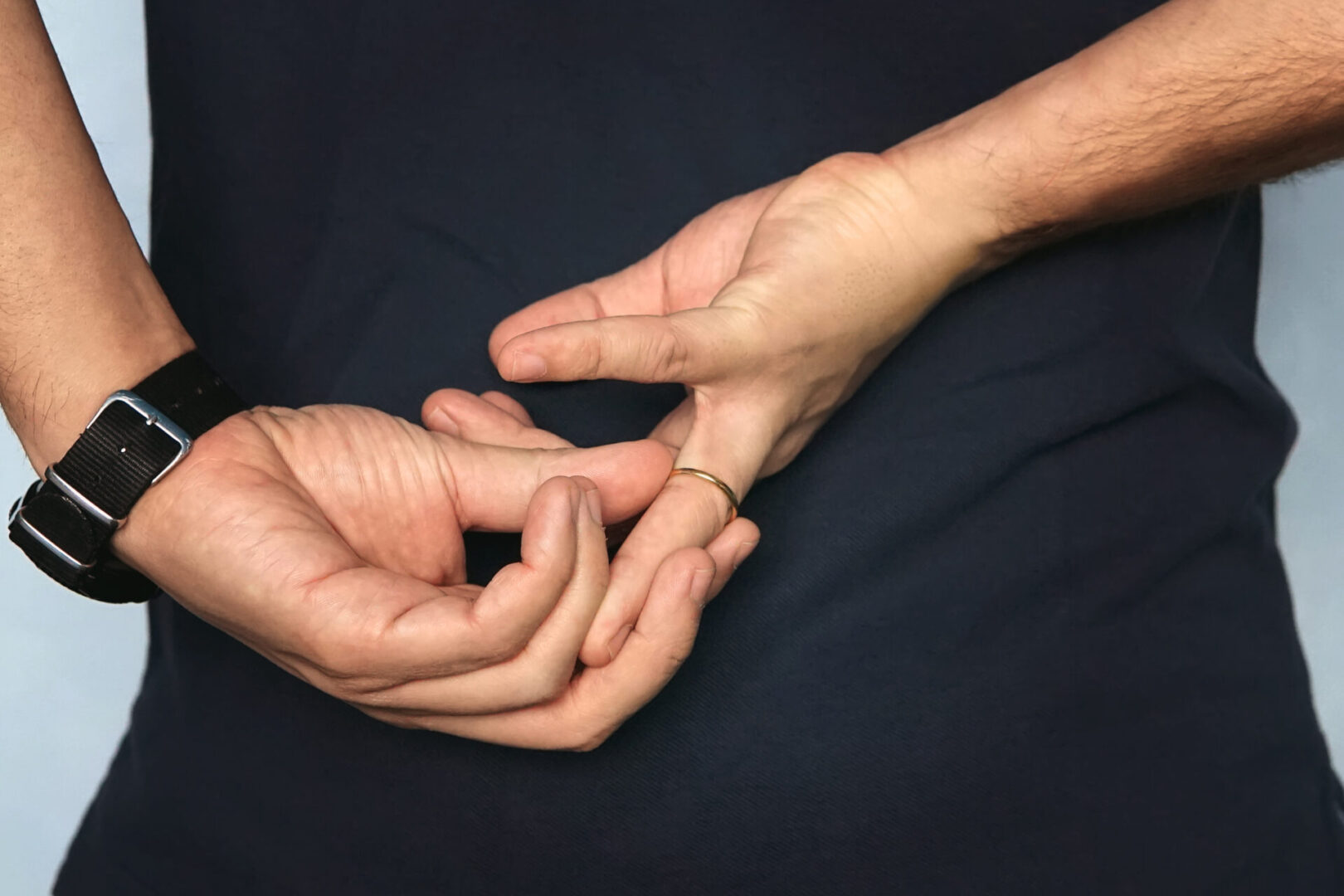 Two hands holding one another with a wedding ring on.